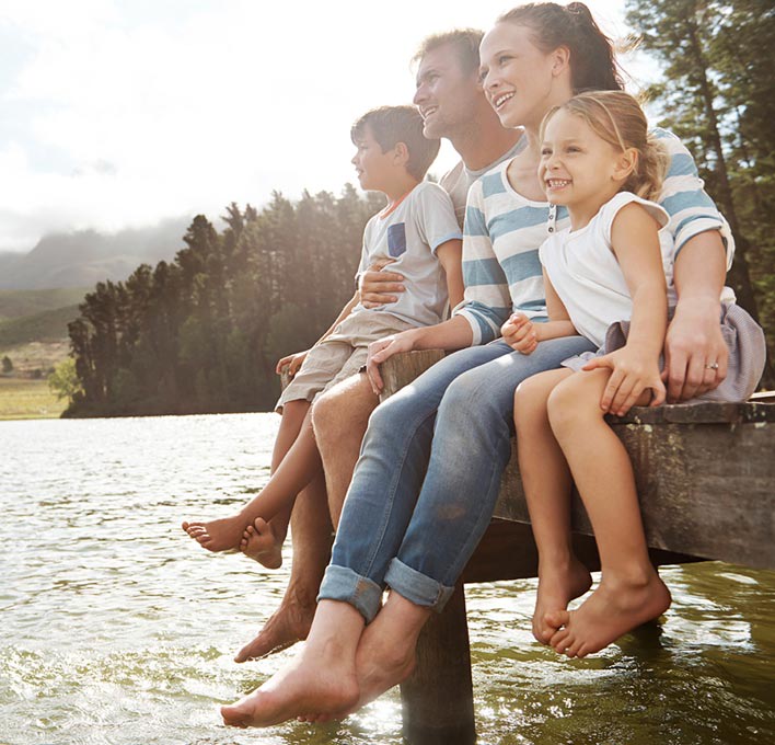 A family of four sat on the edge of a pier, looking at the view